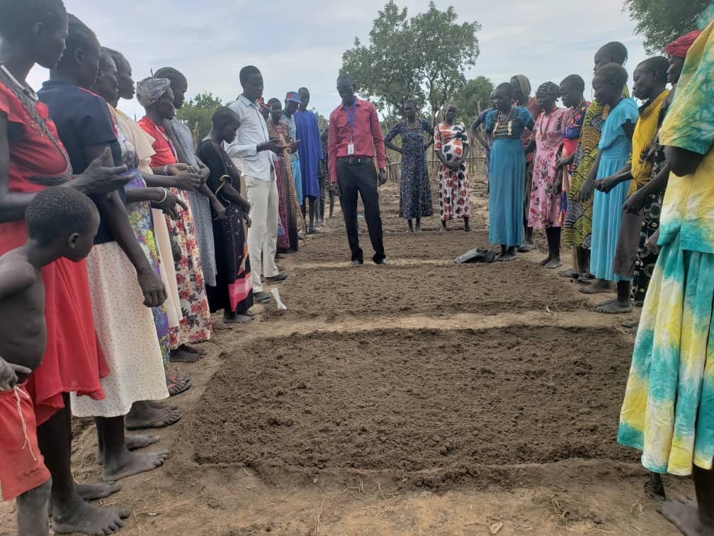 Community members gathered near prepared farm plots.